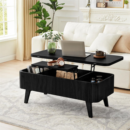 Black lift-top coffee table in a living room setting with a laptop, books, and decorative items.